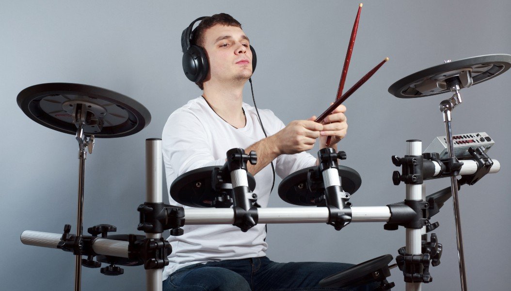 Man plays the drums with headphones on